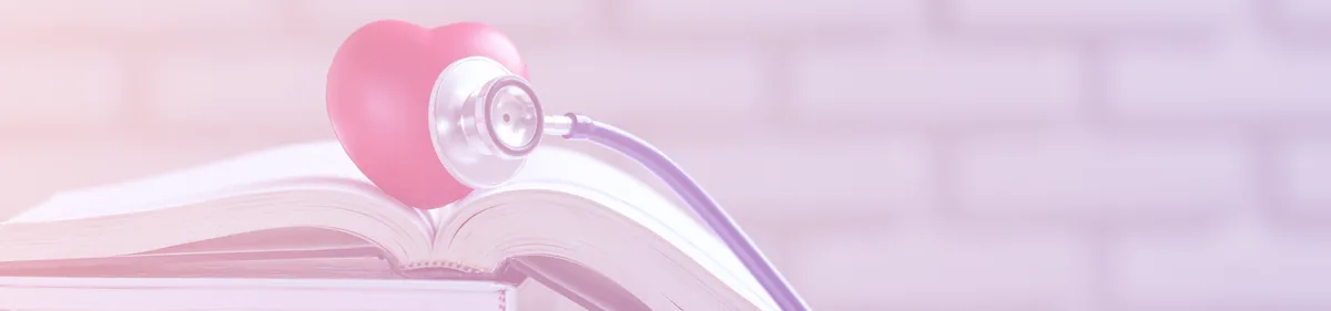 Un stéthoscope au pavillon en forme de cœur rose, posé sur un livre ouvert